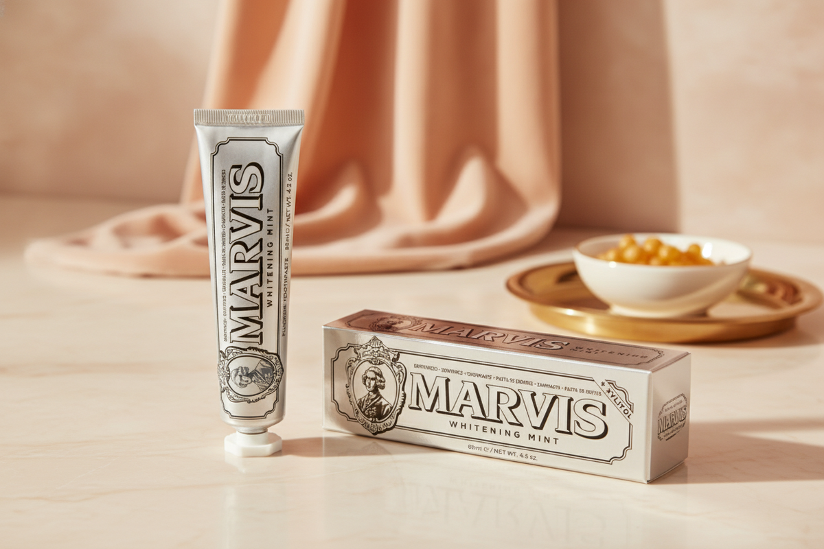 Marvis Whitening Mint Toothpaste tube and box on a warm cream surface with soft peach and golden honey accents in the backgro